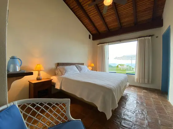 Habitación 03: cama king con puerta azul y vista a la piscina